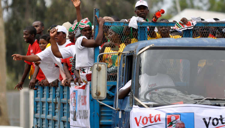 Supporters of Mozambique's President Armando Guebuza's ruling FRELIMO party distribute pamphlets in Maputo, on the last day of campaigning