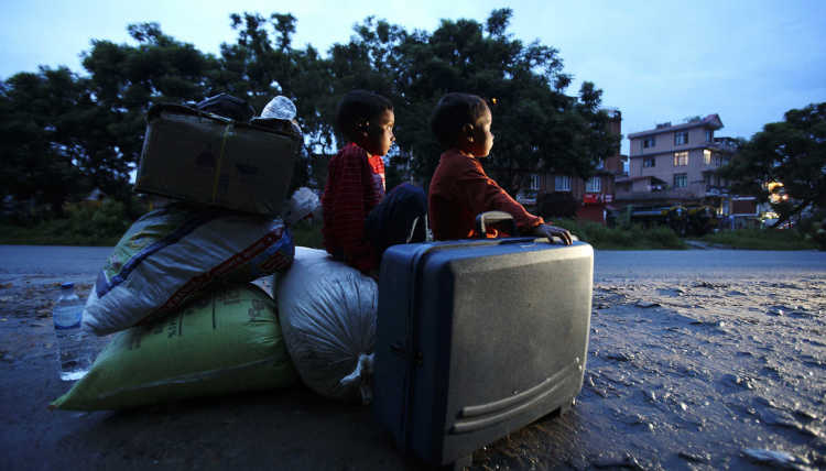 Nepalese refugee children sit on their family's belongings on the street after the civil war.