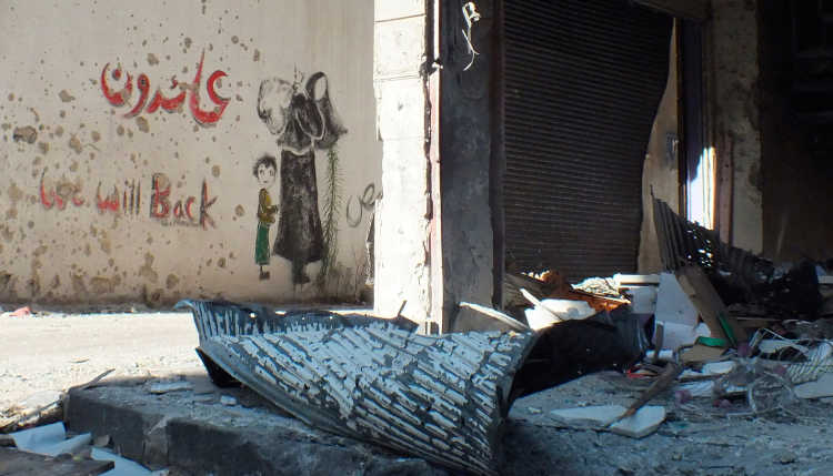 Graffiti im zentralen Homs im Jahr 2012. Das Arabisch bedeutet: "Wir werden wiederkommen."