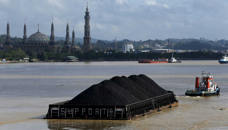 A tug boat pulls a coal barge along the Mahakam River in Samarinda, East Kalimantan province, Indonesia