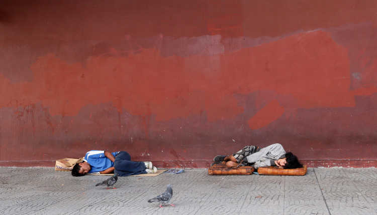 Two homeless people lying on the pavement in Argentina.