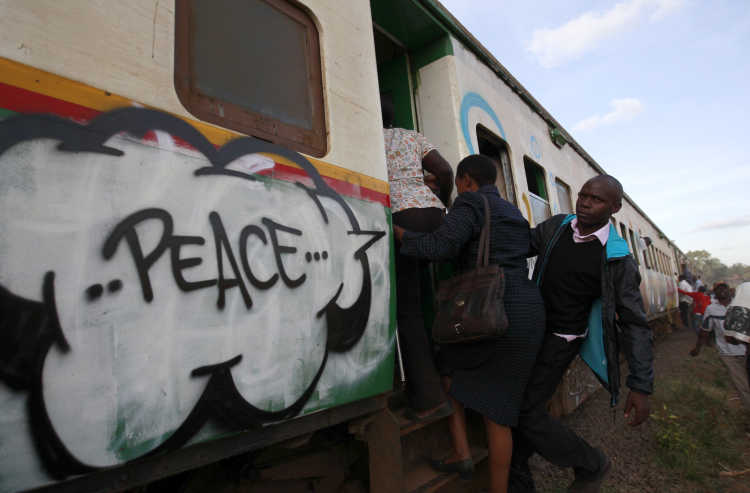 Pendler besteigen einen Zug in Nairobi, auf dem ein Friedensgraffiti aufgesprüht ist.