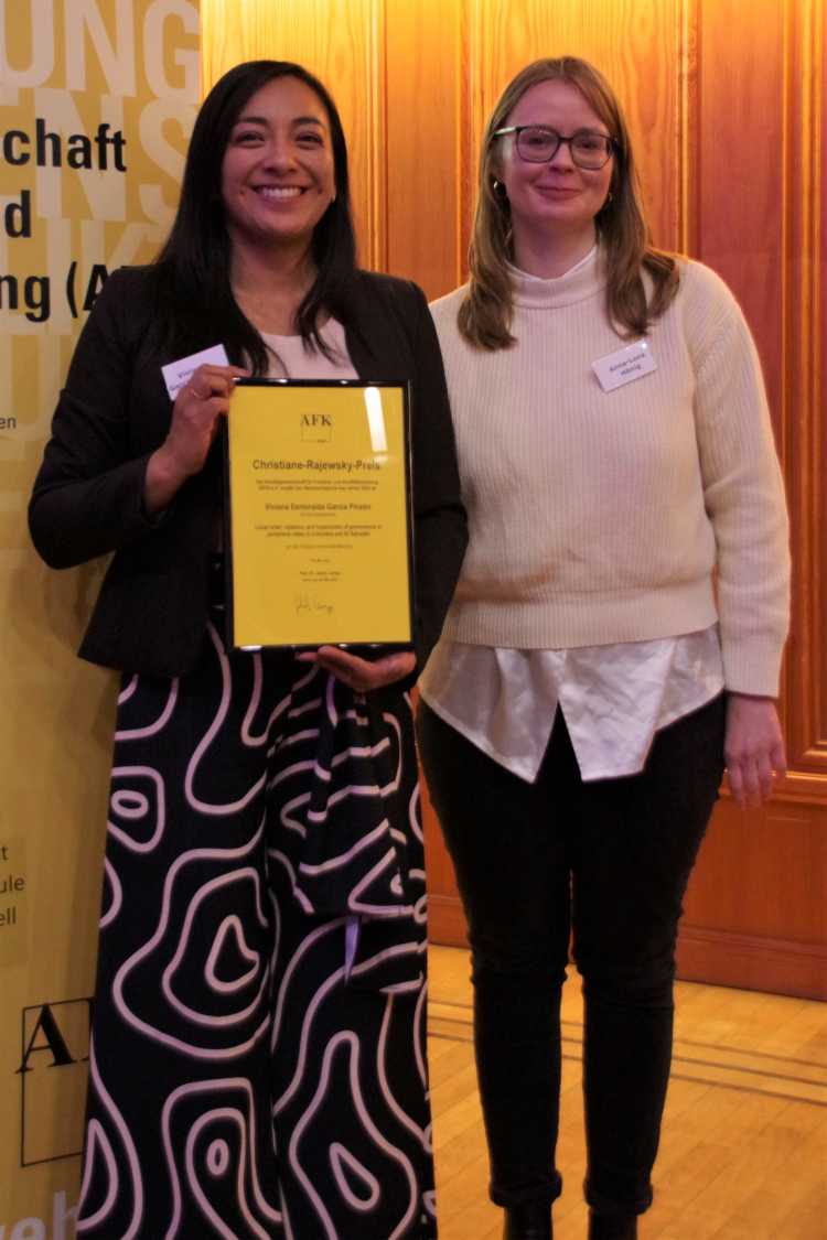 Viviana García Pinzón holds the certificate of the Christiane Rajewsky Prize 2023, Anna-Lena Hönig stands next to her.