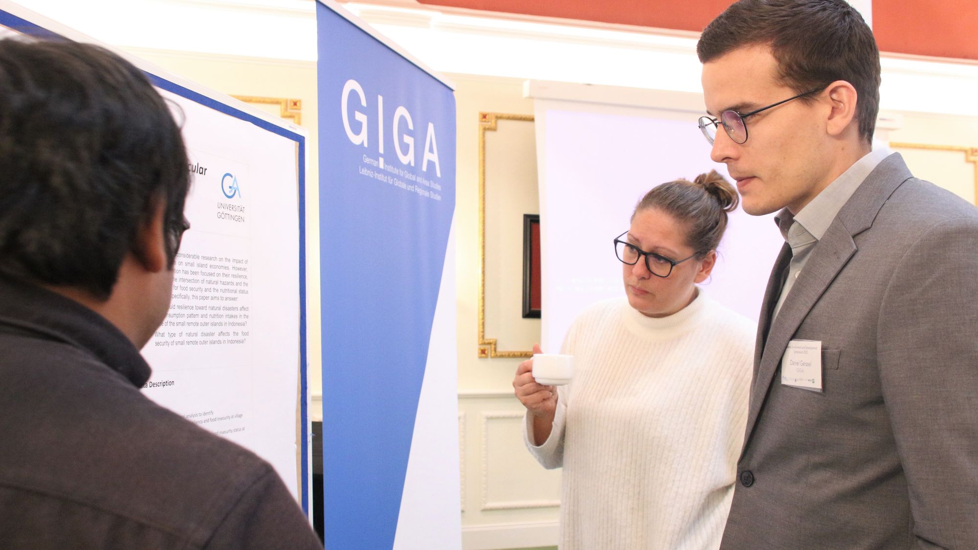 Participants of Leibniz Environment and Development Symposium 2022 chat during poster session in conference room at Baseler Hof, Hamburg.