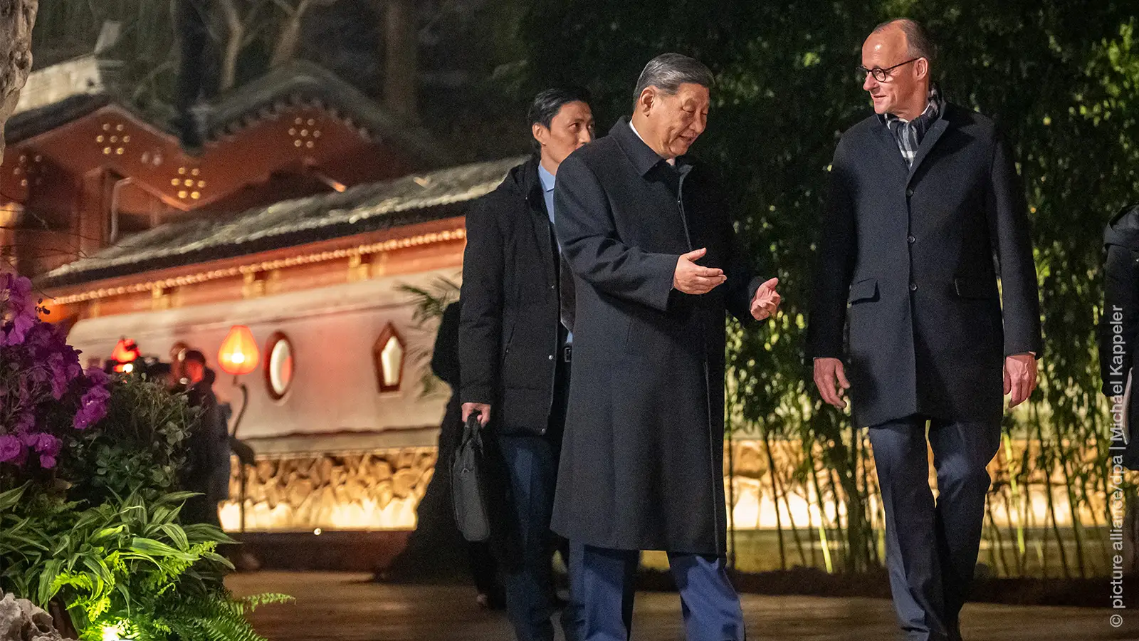 Bundeskanzler Friedrich Merz (CDU,r) geht neben Xi Jinping, Präsident von China, am Staatsgästehaus und begleitet von Dolmetschern zu einem Abendessen. Merz besucht erstmals als Bundeskanzler China.