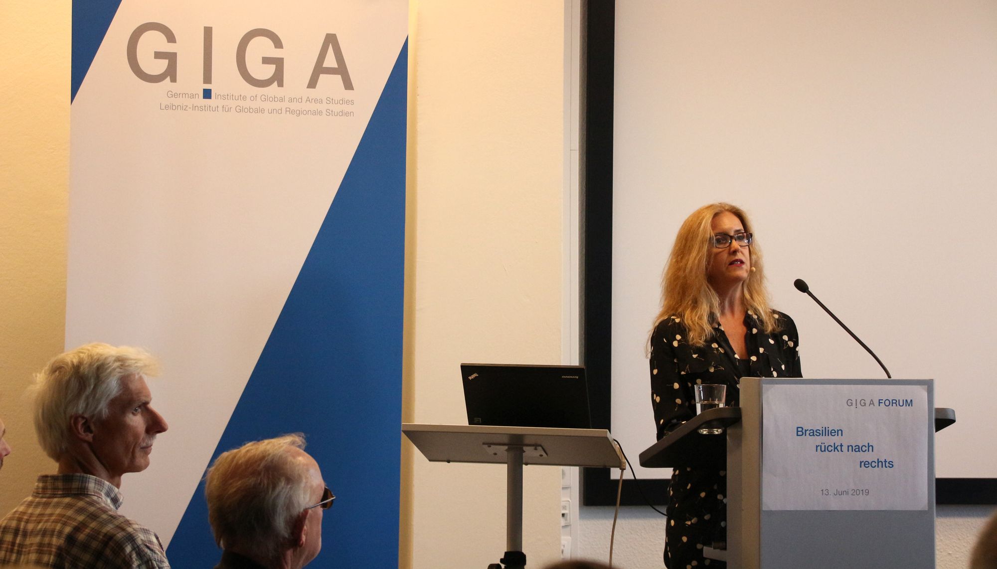 Foto von Dr. Mariana Llanos auf Podium vor Publikum