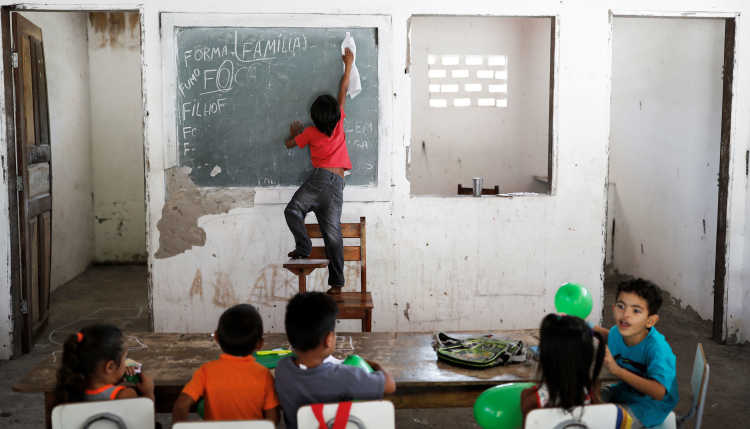Ein Schüler in einem brasilianischen Klassenraum wischt die Tafel ab.