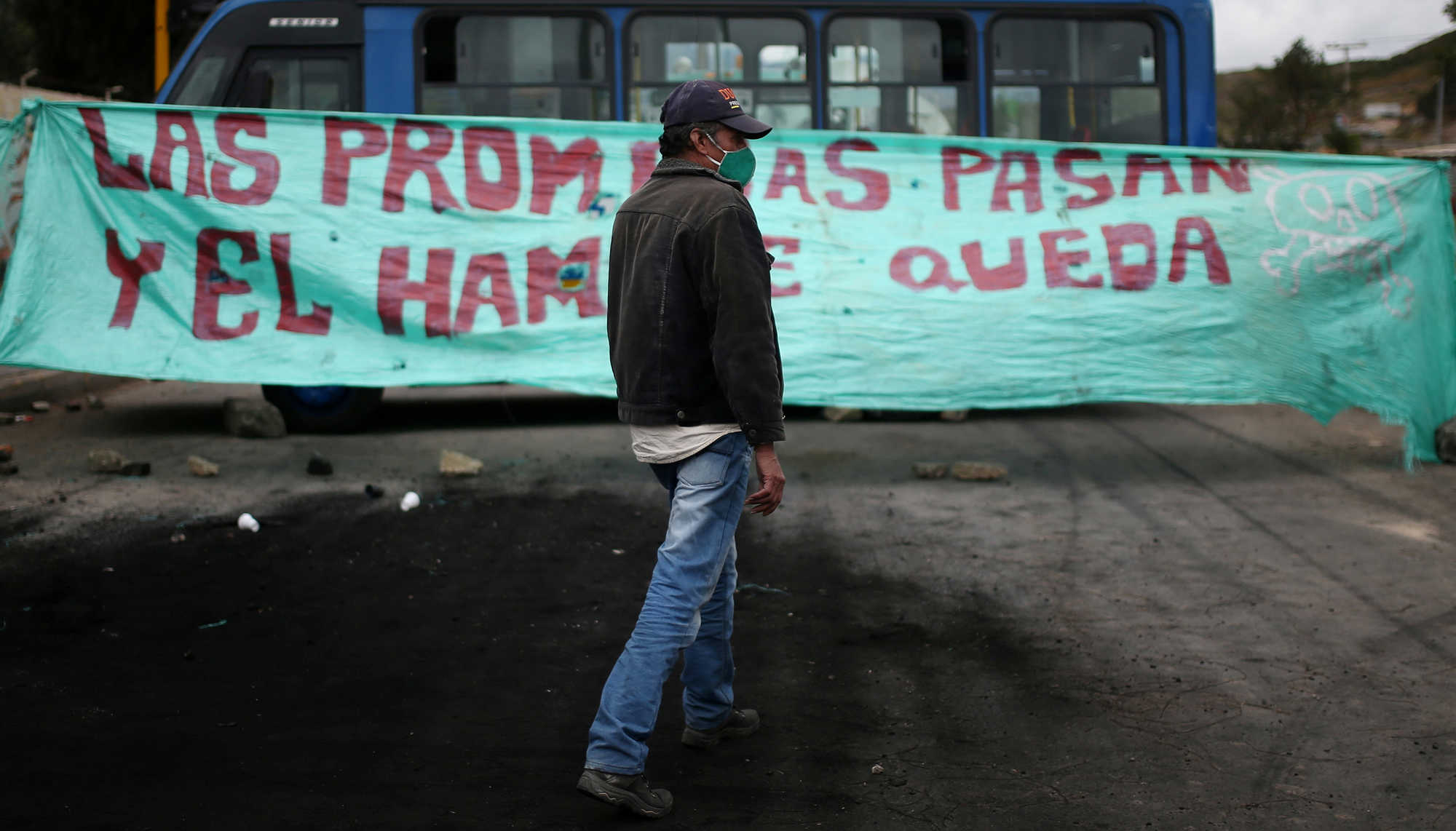 Picture of a demonstrator wearing a mask in front of a sign