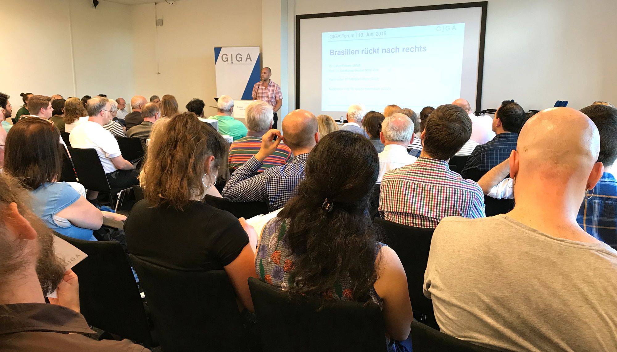 Foto von Dr. Daniel Flemes auf Podium vor Publikum