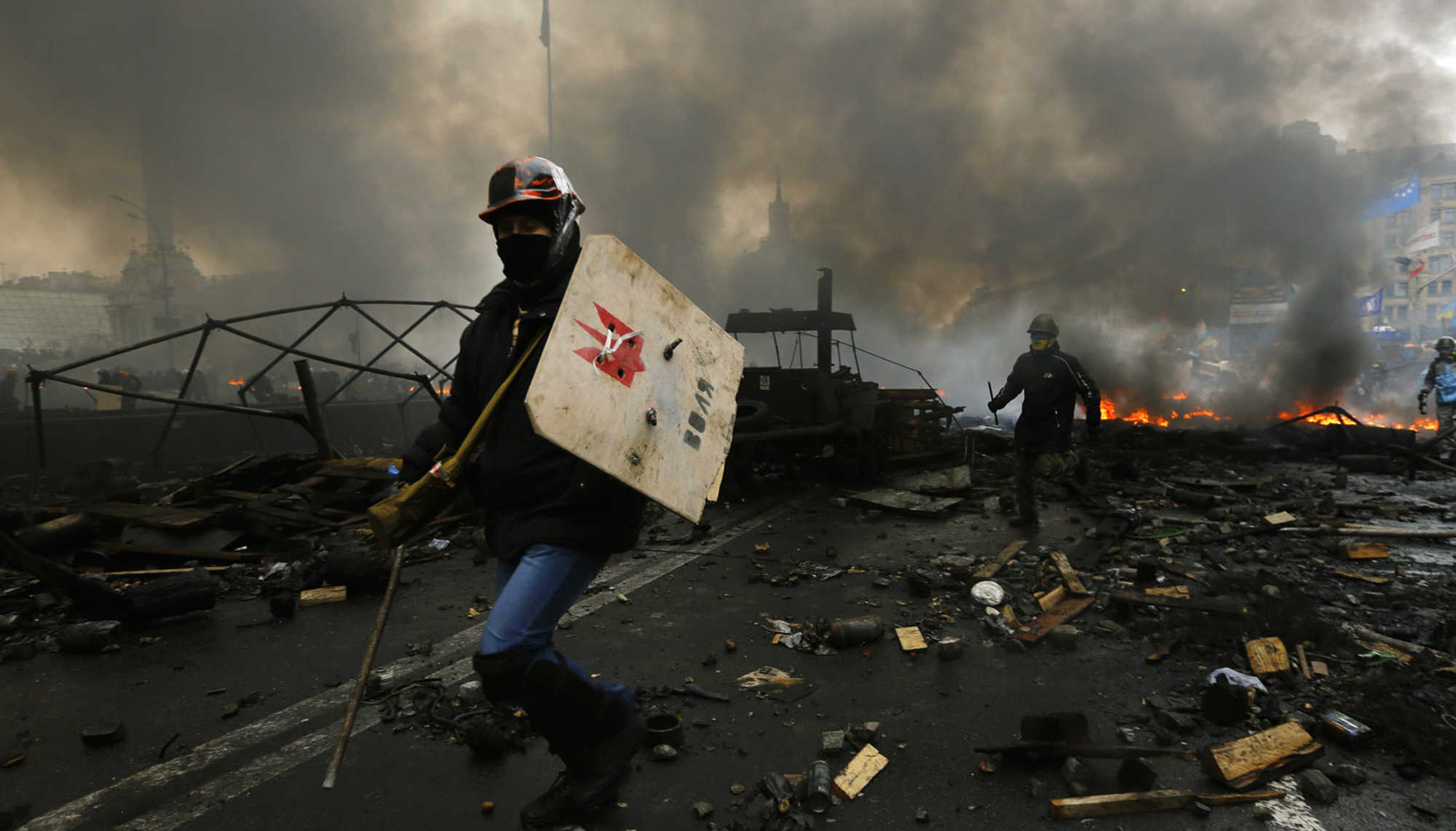 Two demonstrators in Kiev / Ukraine run on the street blocked by burning barricades.