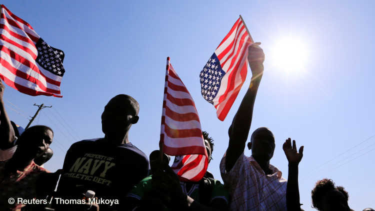 Residents wave the U.S. national flag ahead of the visit by the former U.S. President Barack Obama to his ancestral Nyangoma Kogelo village in Siaya county, western Kenya