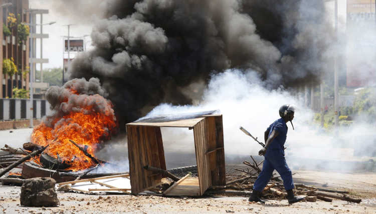Ein Polizist geht bei einem Protest gegen den burundischen Präsidenten Pierre Nkurunziza an einer verbrannten Barrikade vorbei.