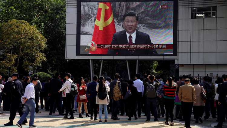 People are watching a speech by China's President Xi Jinping on a big screen. 