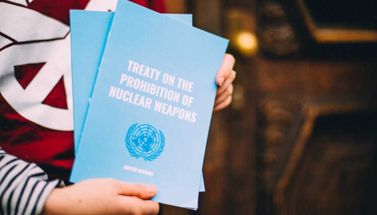 Eine Person ist hält eine Kopie des UN-Vertrags über das Verbot von Kernwaffen.