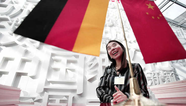 Eine Hostess scherzt hinter einer deutschen und einer chinesischen Flagge vor dem chinesischen Pavillon auf der Frankfurter Buchmesse.