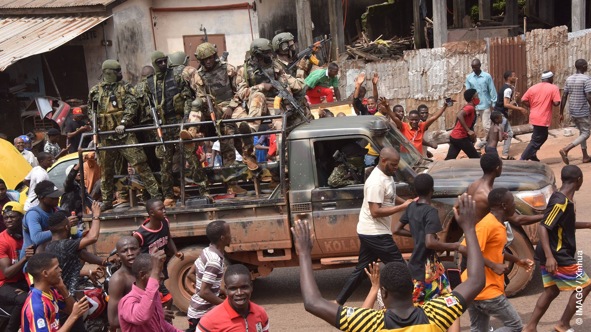 People are seen around members of Guinea's special forces in Conakry, Sept. 6, 2021.