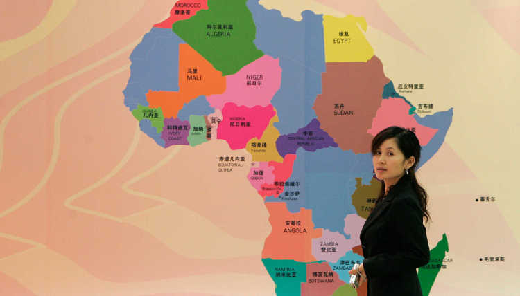 A woman stands in front of a map of Africa.
