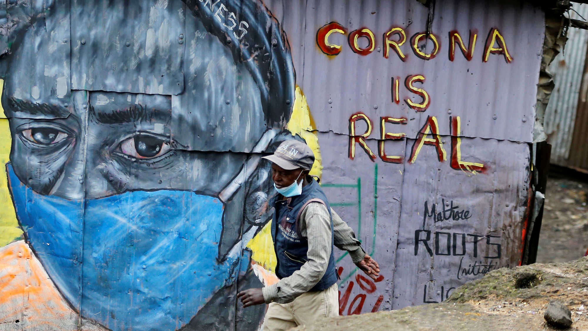 Man with mask walking past a graffiti