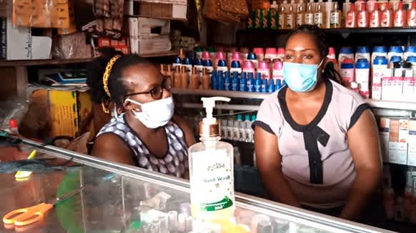 Two women with face masks are standing in a store in Uganda. 
