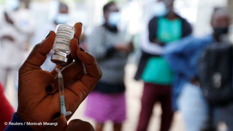 A health worker holding a syringe and a vial of COVID-19 vaccine, Nairobi, Kenya.