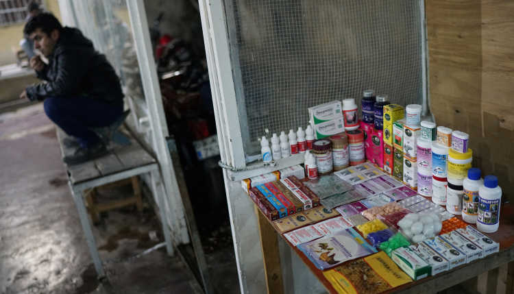 Ein Mann sitzt vor einem Straßenverkaufsstand mit Medikamenten.